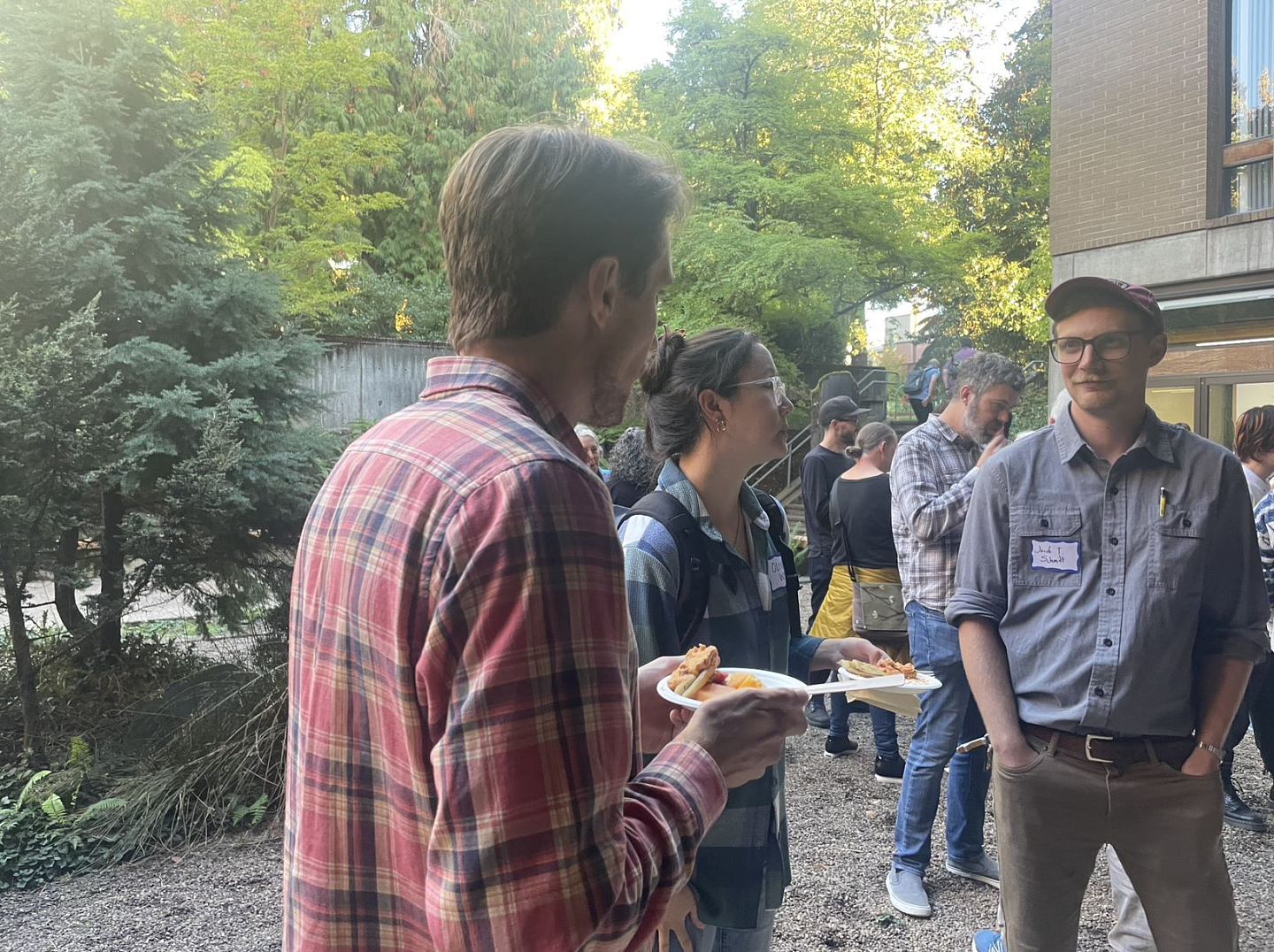 Photo of three students standing in McKenzie courtyard with food and talking with each other.