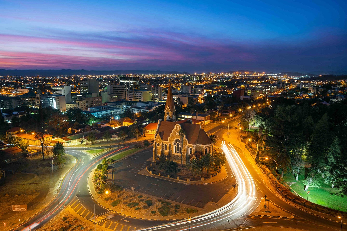 Nighttime in a large city where cars are driving by a church landmark