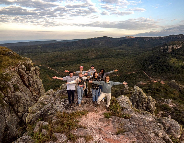 Group of people standing on a top of mountain holding out their hands