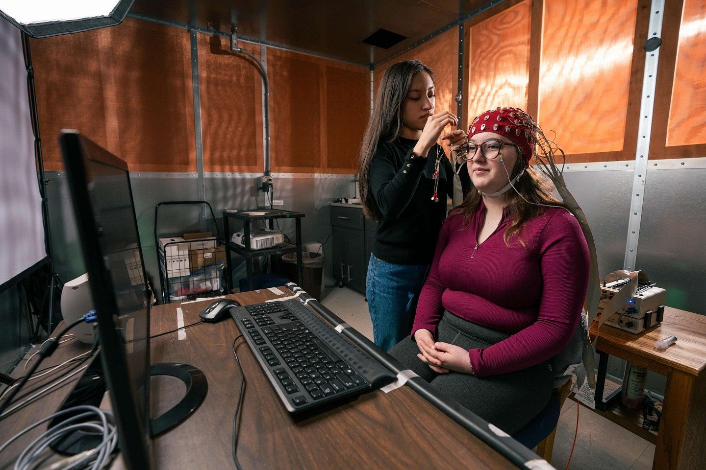 a person puts a dome shaped helmet on a student to track brain activity