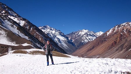 student on snow-covered slope with mountain range in background