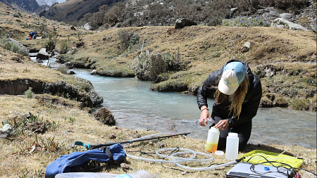 Holly Moulton pours a liquid into a container outside