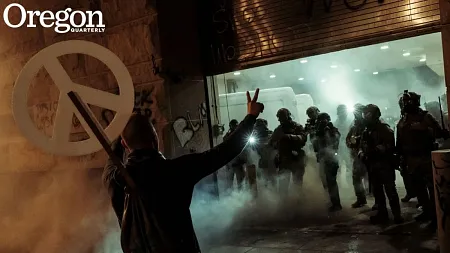 a protester giving the peace sign to police during a protest in Portland