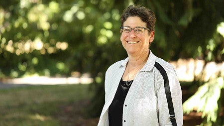 a portrait of a person posing with greenery behind her