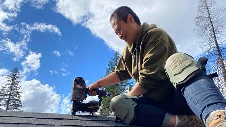 a person on a roof with a nail gun