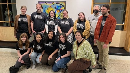 students standing in two rows for photo wearing prison education program shirts