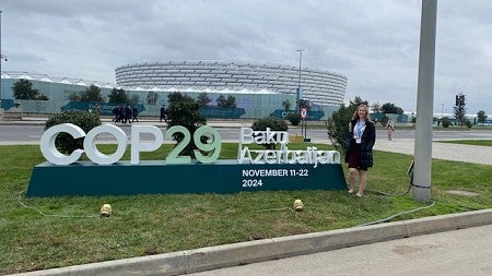 a person standing beside a sign that says COP29