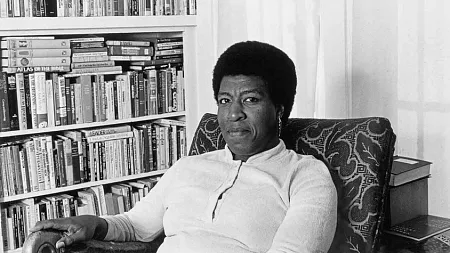 octavia butler sitting by a bookshelf