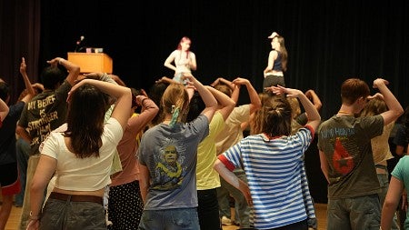 two people on a stage instructing a group of students how to dance