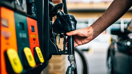 hand putting away a gas pump at a bank of gas pumps