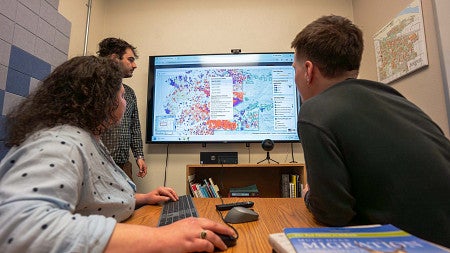 three people looking at a map on a computer screen