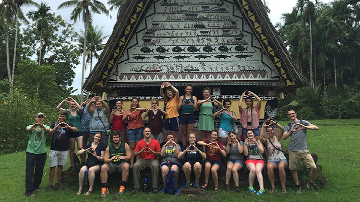 large group of students posing in front of monument