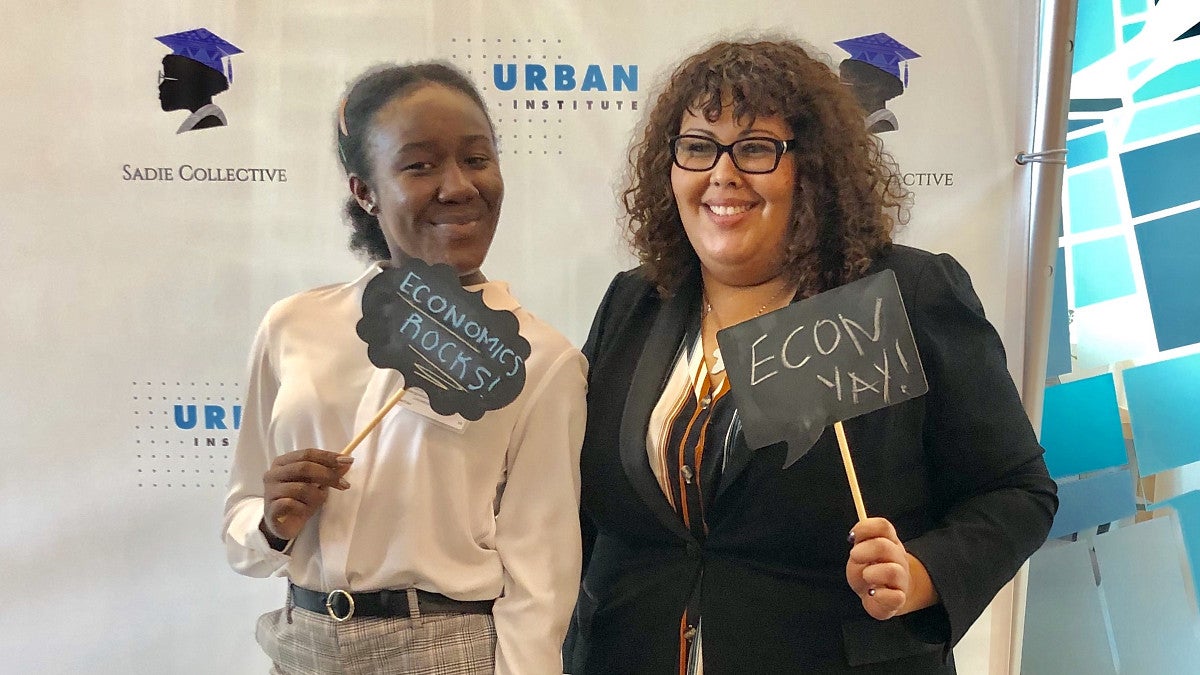 Two graduate students holding up signs about how great econ is