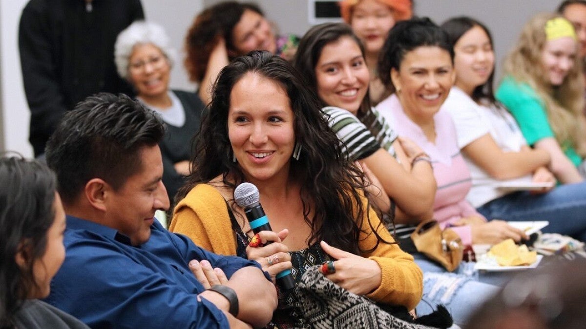 IRES faculty member sitting in a group of people holding a microphone