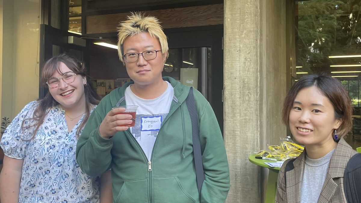 Three students smiling at the camera outside of McKenzie Hall