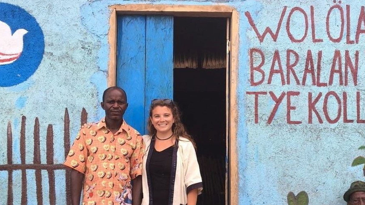 a woman poses with a man outside a blue building