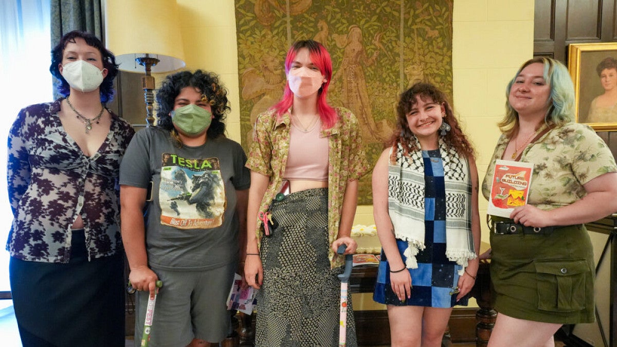 Students posing in front of a table with magazines on it