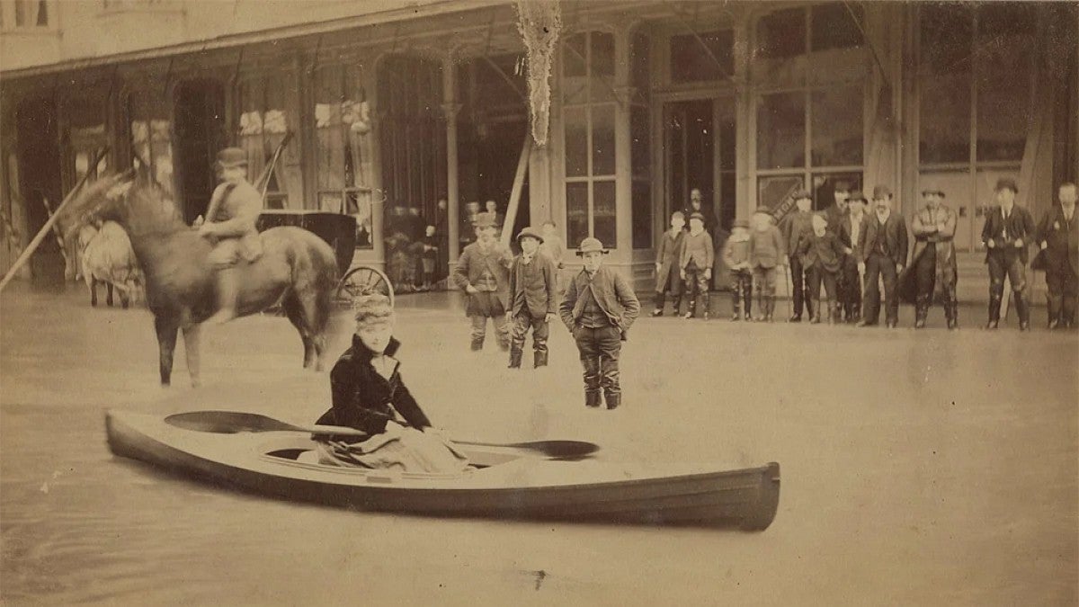 Woman in a boat floating down the street.