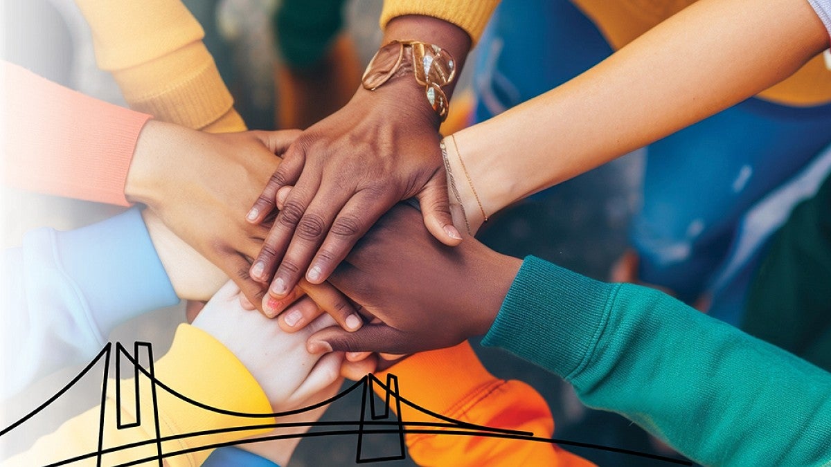 People stacking hands on top of each other in show of collaboration