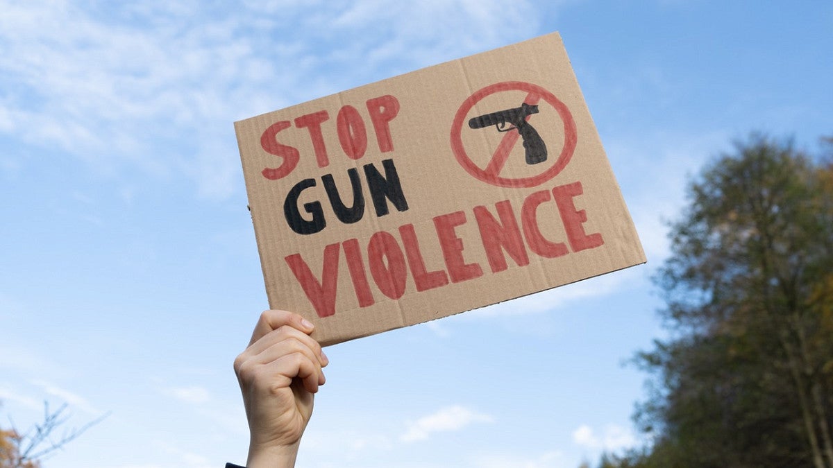 a person holding a sign that says stop gun violence