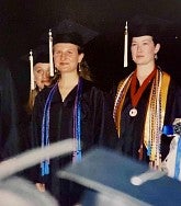 woman wearing graduation gown and cap walking in a procession with another woman