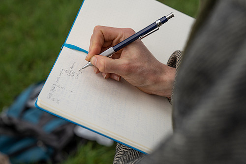 student making research notes in field book