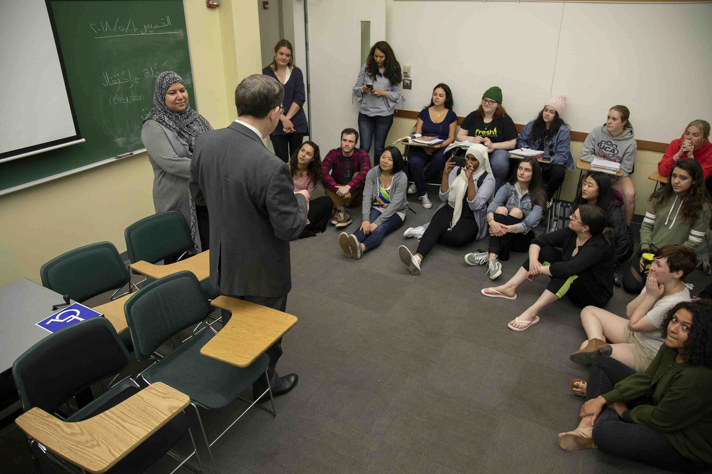 an Arabic classroom with students listening to someone speaking