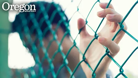a hand gripping a chain-link fence