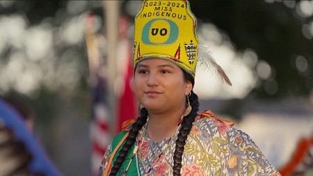 A woman wearing Native American clothing and a crown that says Miss Indigenous UO