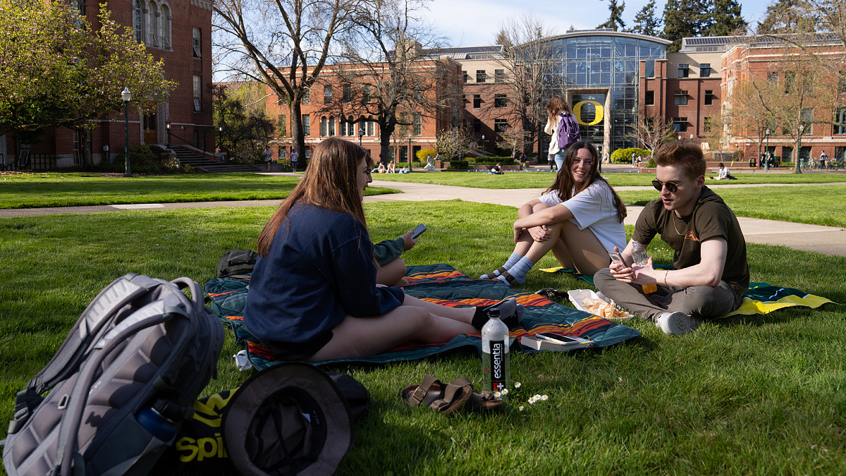group of students sitting on campus lawn in spring
