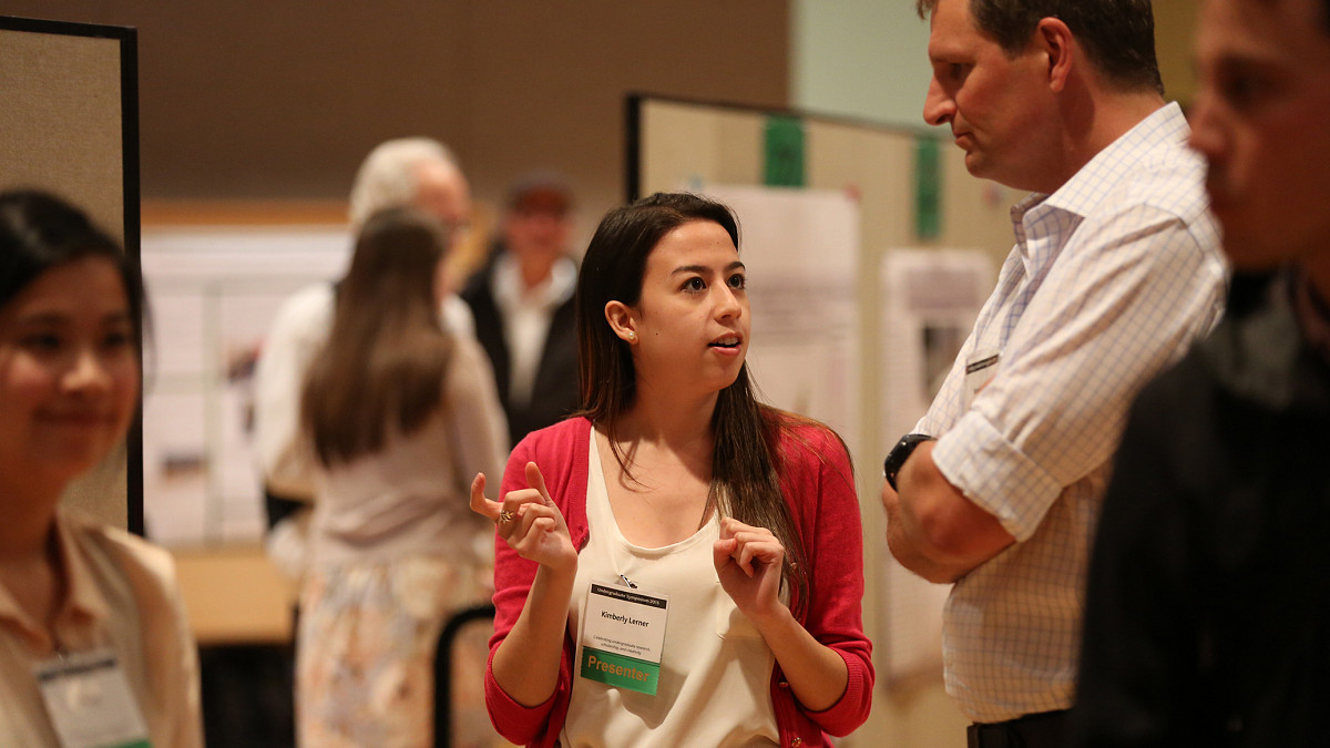 student presenter talking to attendee at symposium