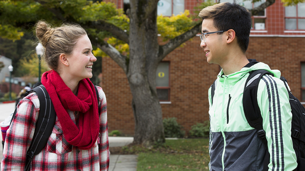 two students smiling at each other outdoors on campus